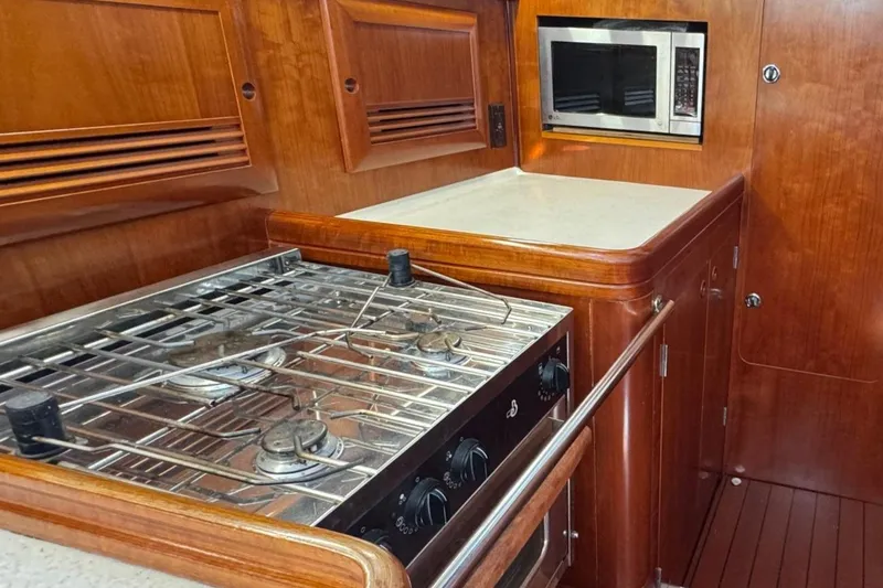 Slide: The Image of Luxurious 2005 Beneteau 473 yacht kitchen with stove and microwave, featuring elegant wood cabinetry. - 35