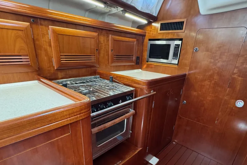 Slide: The Image of Luxurious 2005 Beneteau 473 yacht kitchen with wood cabinetry, stove, and microwave. - 4