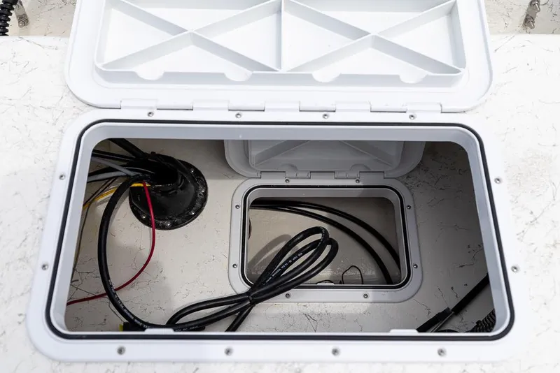 Slide: The Image of Open storage compartment on 2026 Coastal Skiff 231 boat, showing wiring and cables. - 15
