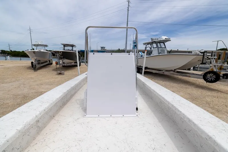 Slide: The Image of 2026 Coastal Skiff 231 boat on trailer, surrounded by other boats, under a clear sky. - 18