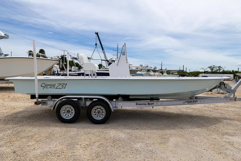 Slide: The Image of 2026 Coastal Skiff 231 boat on trailer, parked outdoors under a cloudy sky. - 5