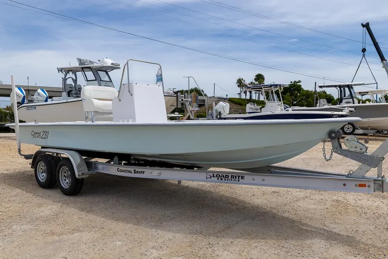 Slide: The Image of 2026 Coastal Skiff 231 boat on trailer in marina setting. - 6