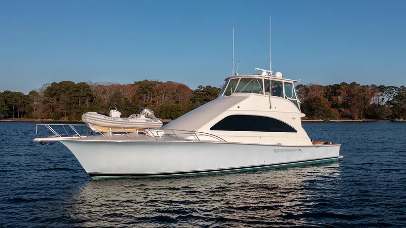 The Image of 2004 Ocean Yachts 57 Convertible cruising on calm waters, with trees in the background. - 1