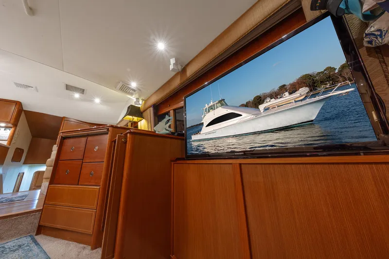 Slide: The Image of Interior of 2004 Ocean Yachts 57 Convertible with wooden cabinetry and yacht image on TV. - 15