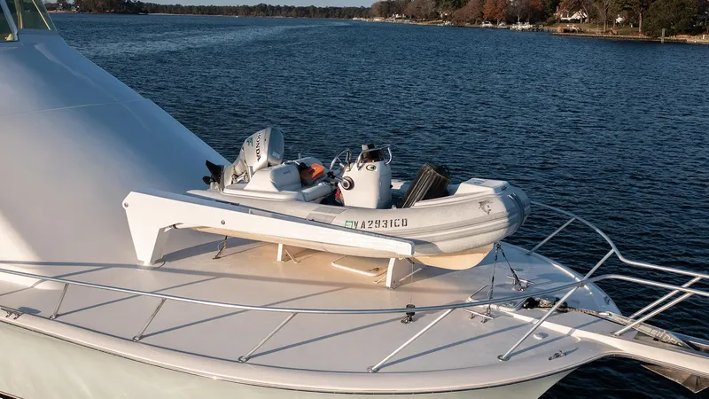 Slide: The Image of 2004 Ocean Yachts 57 Convertible with dinghy on deck, cruising on a serene waterway. - 10