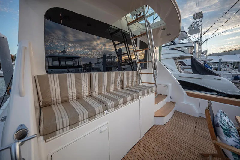 Slide: The Image of 2004 Ocean Yachts 57 Convertible yacht with striped seating and wooden deck at sunset. - 45