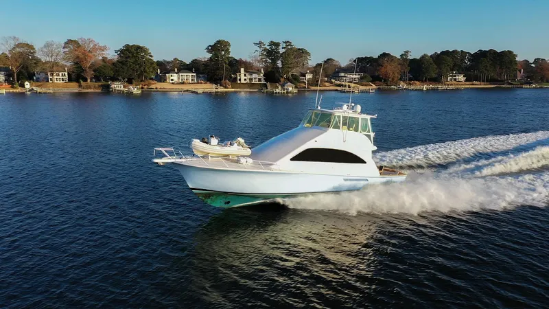 Slide: The Image of 2004 Ocean Yachts 57 Convertible cruising on a serene lake with waterfront homes. - 8