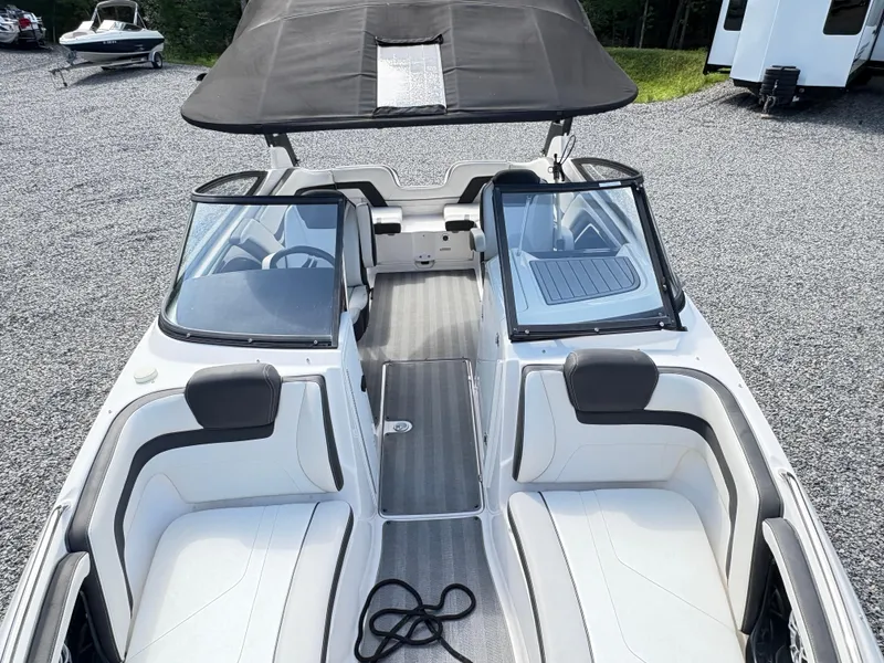 Slide: The Image of 2019 Yamaha Boats 242 Limited E-Series interior with seating and canopy, parked on gravel. - 12