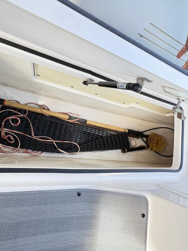 Slide: The Image of Storage compartment in 2019 Yamaha Boats 242 Limited E-Series, containing a net and cleaning brush. - 18
