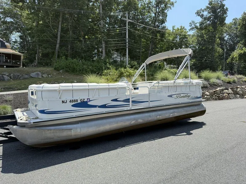Slide: The Image of 2006 Bentley Pontoons 240 CRUISE on trailer, parked on a road with trees in background. - 12