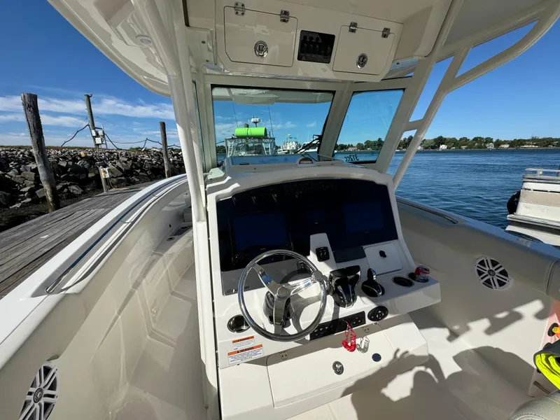 Slide: The Image of 2023 Sailfish 312 CC boat cockpit with steering wheel and controls, docked by the water. - 10