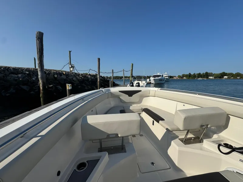 Slide: The Image of 2023 Sailfish 312 CC boat interior with seating, docked by a calm waterfront. - 12