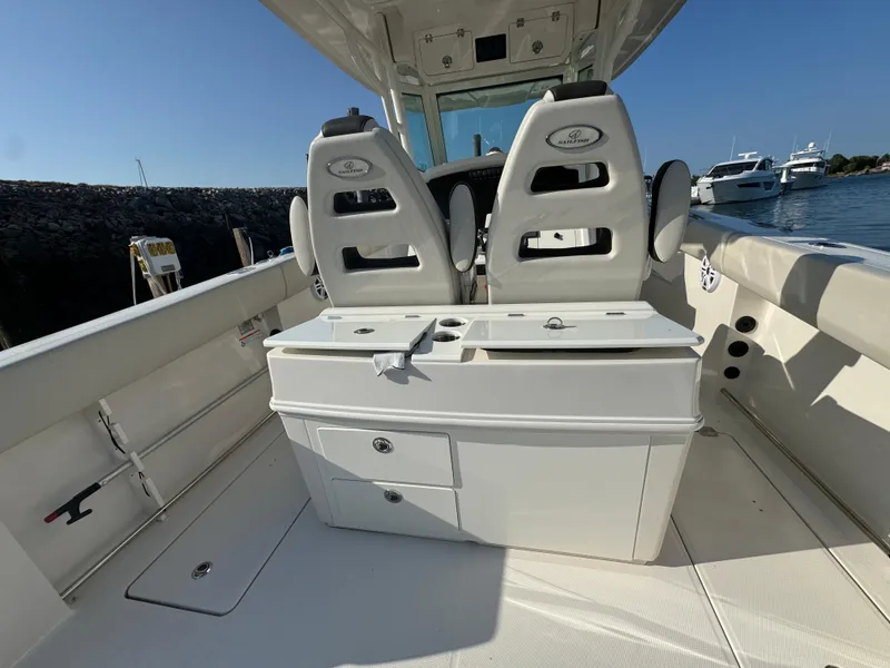 Slide: The Image of 2023 Sailfish 312 CC boat interior with dual seats and storage, docked by the water. - 6