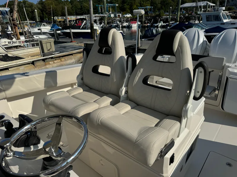 Slide: The Image of 2023 Sailfish 312 CC boat interior with dual seats and steering wheel at marina. - 8