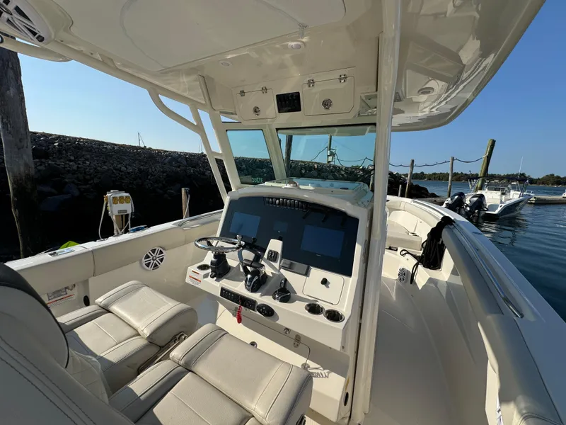 Slide: The Image of 2023 Sailfish 312 CC boat interior with modern dashboard and seating, docked by the water. - 9