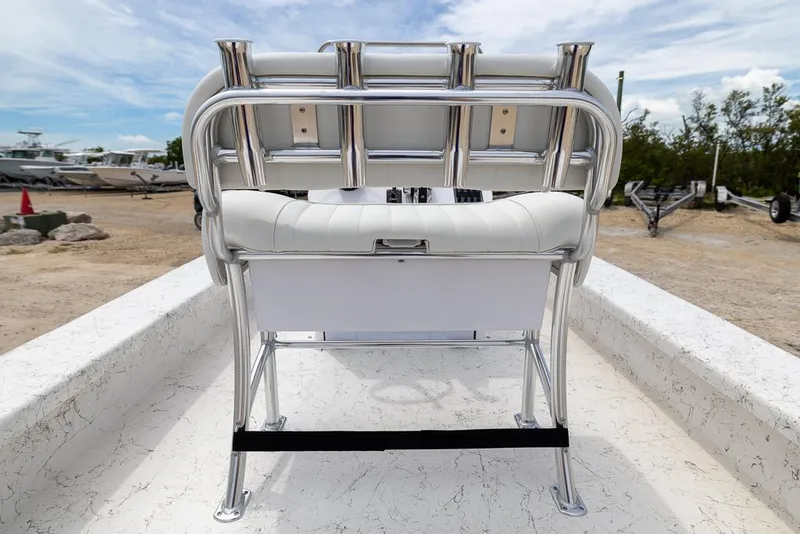 Slide: The Image of 2026 Coastal Skiff 231 boat seat with rod holders, parked on a sandy lot. - 12