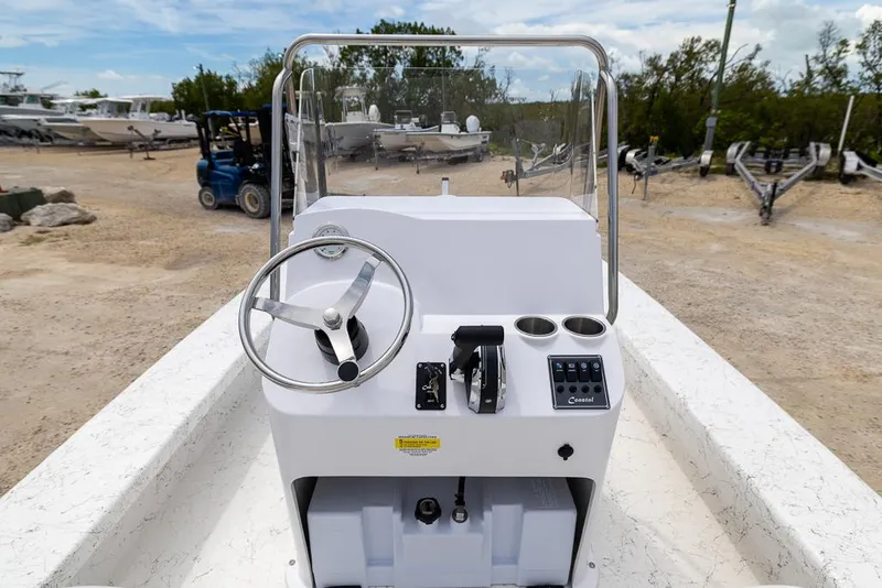 Slide: The Image of 2026 Coastal Skiff 231 boat console with steering wheel and controls, parked outdoors. - 8