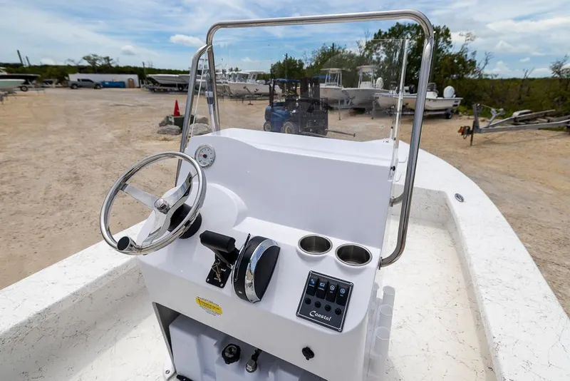 Slide: The Image of 2026 Coastal Skiff 231 boat console with steering wheel and controls, parked outdoors. - 9