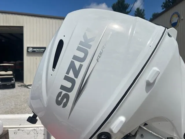Slide: The Image of White Suzuki outboard motor on a Carolina Skiff J1450, 2000 model, near a boat dealership. - 6
