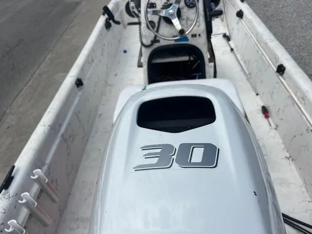 Slide: The Image of 2000 Carolina Skiff J1450 boat interior with 30 HP engine, steering wheel, and controls. - 7
