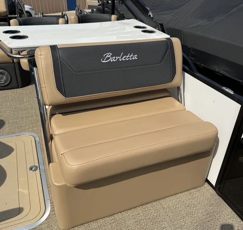 Slide: The Image of A beige seating area on a Barletta Cabrio 24 UE boat, featuring a table and cup holders. - 20