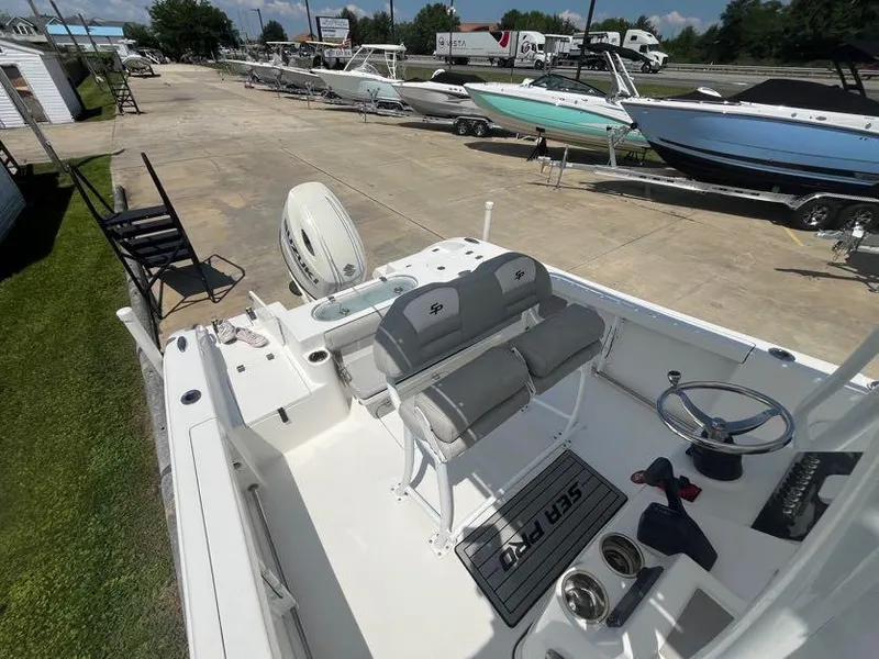 Slide: The Image of 2018 Sea Pro 219 Center Console boat with dual seats and steering wheel, docked outdoors. - 17