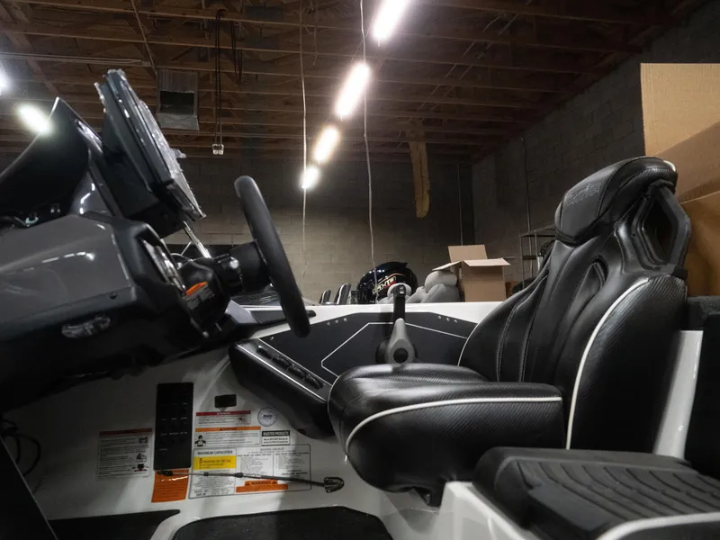Slide: The Image of 2025 Skeeter ZXR20 boat interior with steering wheel and black seats in a warehouse. - 1