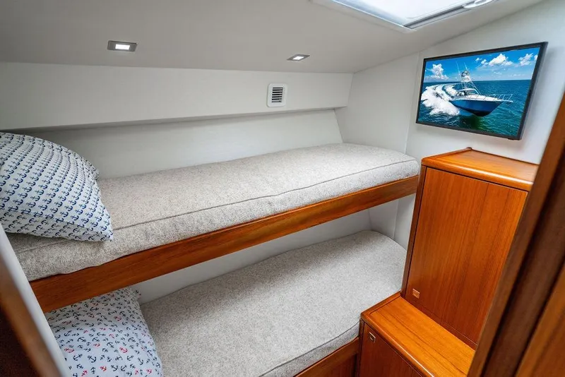 Slide: The Image of 2023 Hatteras GT45X cabin with bunk beds, wooden cabinetry, and nautical-themed decor. - 27