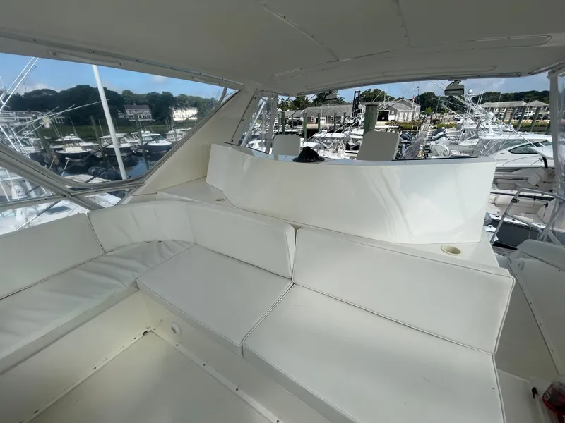 Slide: The Image of Interior view of a 1990 Bertram 50 Convertible yacht with white seating and marina backdrop. - 12
