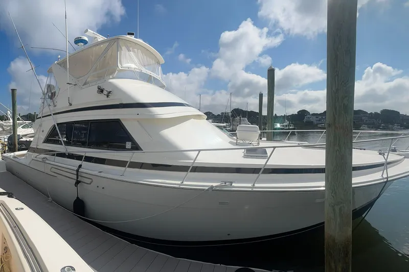 Slide: The Image of 1990 Bertram 50 Convertible yacht docked at marina under blue sky. - 2