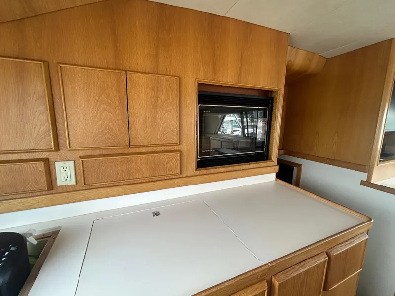 Slide: The Image of Interior of a 1990 Bertram 50 Convertible yacht with wooden cabinetry and built-in microwave. - 20