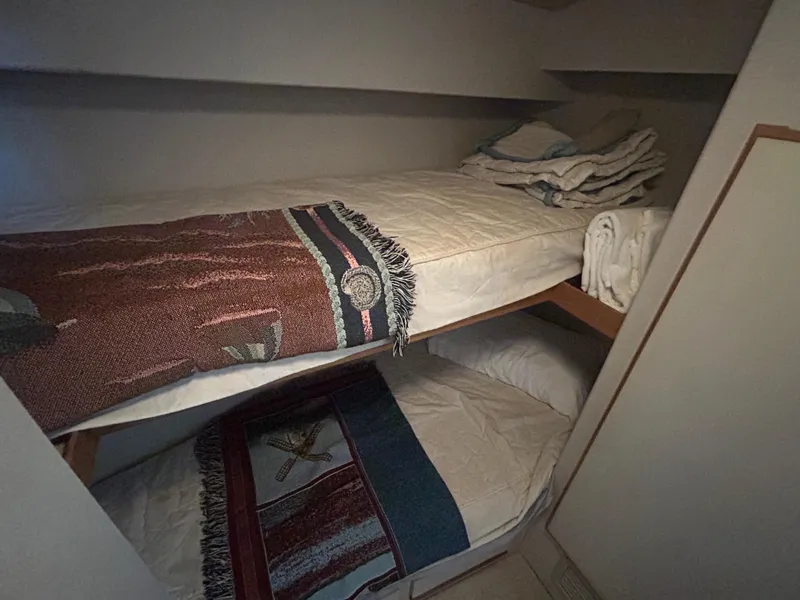 Slide: The Image of Bunk beds in a 1990 Bertram 50 Convertible yacht cabin, with cozy blankets and towels. - 21