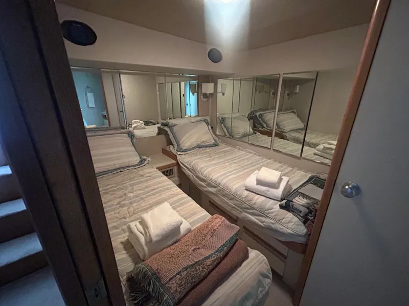 Slide: The Image of Cozy twin cabin in a 1990 Bertram 50 Convertible yacht, featuring mirrored walls and neatly arranged linens. - 22