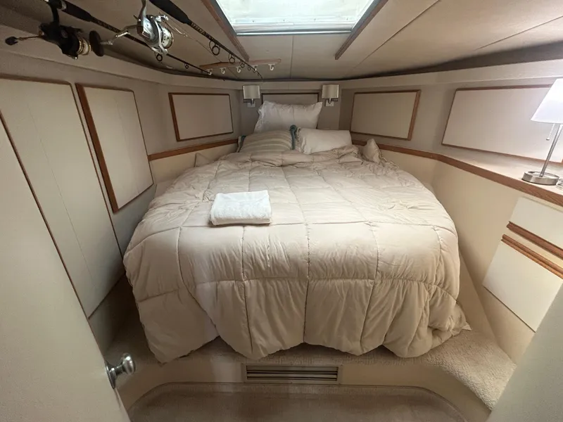 Slide: The Image of Cozy bedroom in a 1990 Bertram 50 Convertible yacht with plush bedding and fishing rods. - 23