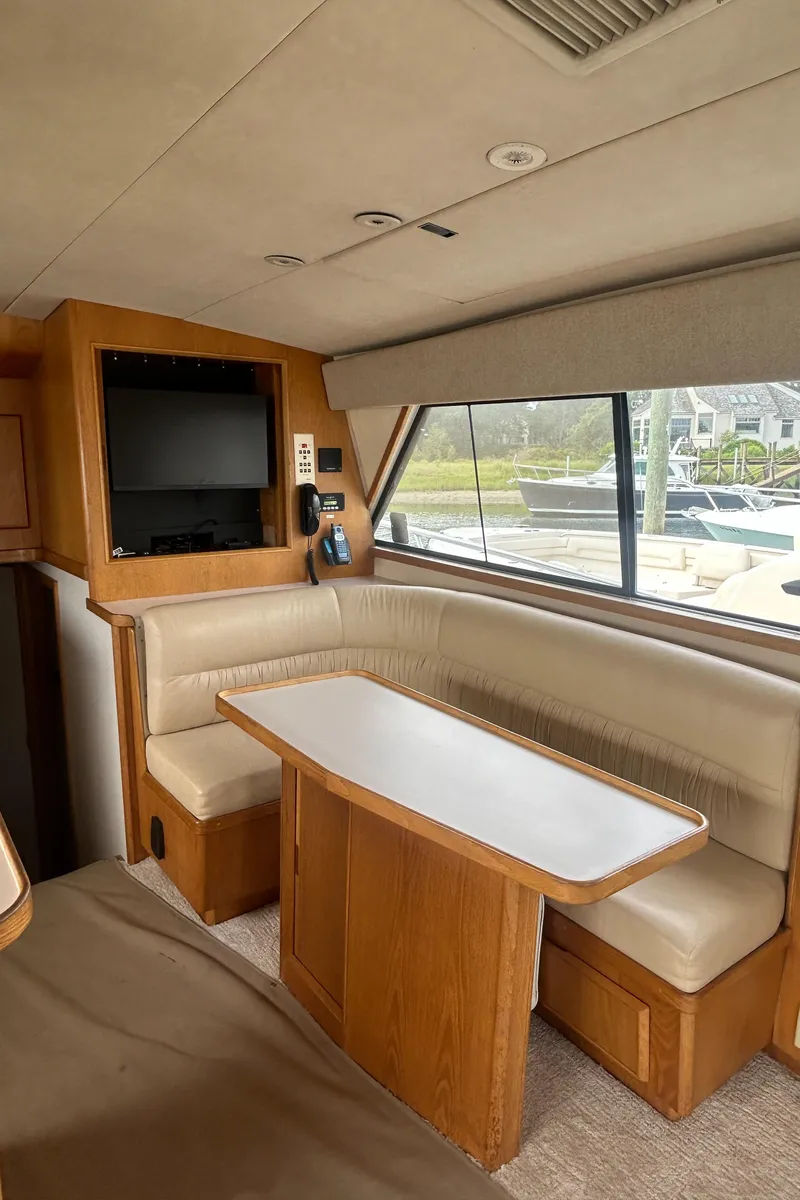 Slide: The Image of Interior of a 1990 Bertram 50 Convertible yacht with beige seating and a wooden table. - 26