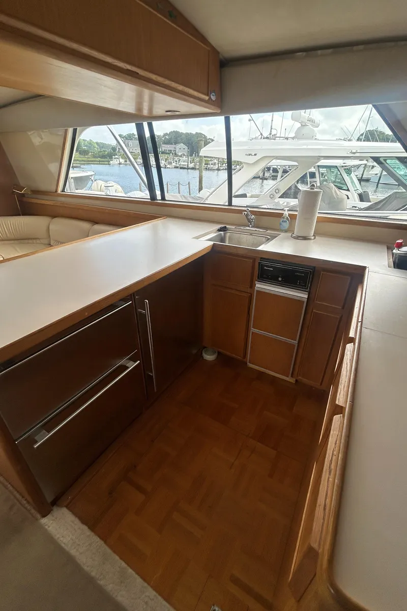 Slide: The Image of Interior of 1990 Bertram 50 Convertible yacht kitchen with wood cabinetry and large windows. - 28
