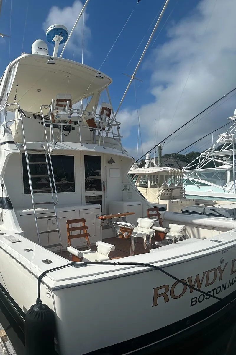 Slide: The Image of 1990 Bertram 50 Convertible yacht docked, featuring spacious deck and seating, under a clear blue sky. - 4