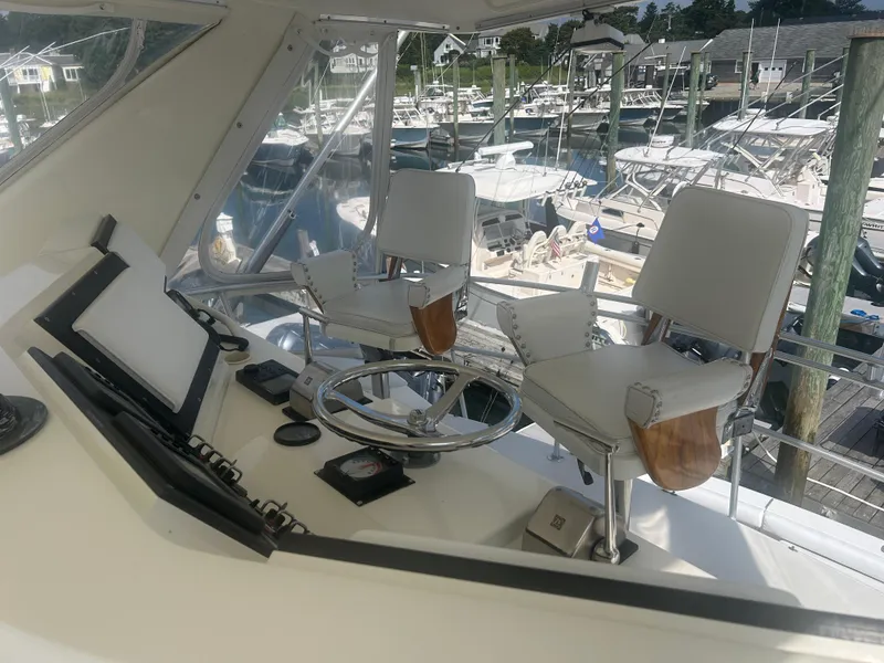 Slide: The Image of 1990 Bertram 50 Convertible helm with dual captain chairs at marina. - 9