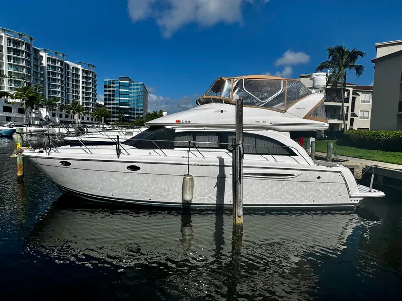 The Image of 2007 Meridian 411 Sedan yacht docked in marina, surrounded by modern buildings and palm trees. - 0