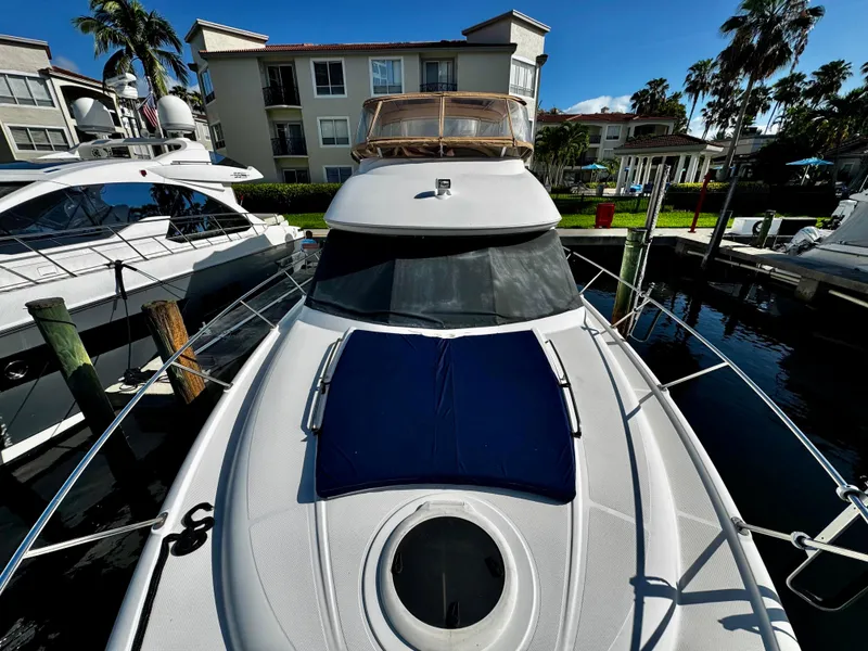 Slide: The Image of 2007 Meridian 411 Sedan yacht docked at marina, surrounded by luxury boats and palm trees. - 2