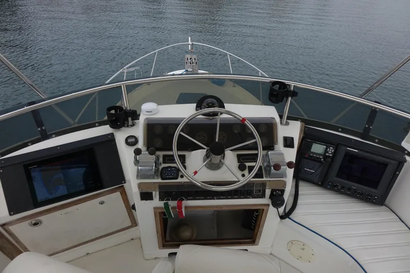 Slide: The Image of 1988 Blackfin 29 Flybridge helm with steering wheel and navigation equipment on calm water. - 14