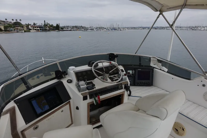 Slide: The Image of 1988 Blackfin 29 Flybridge boat interior with steering wheel and navigation equipment, overlooking marina. - 16
