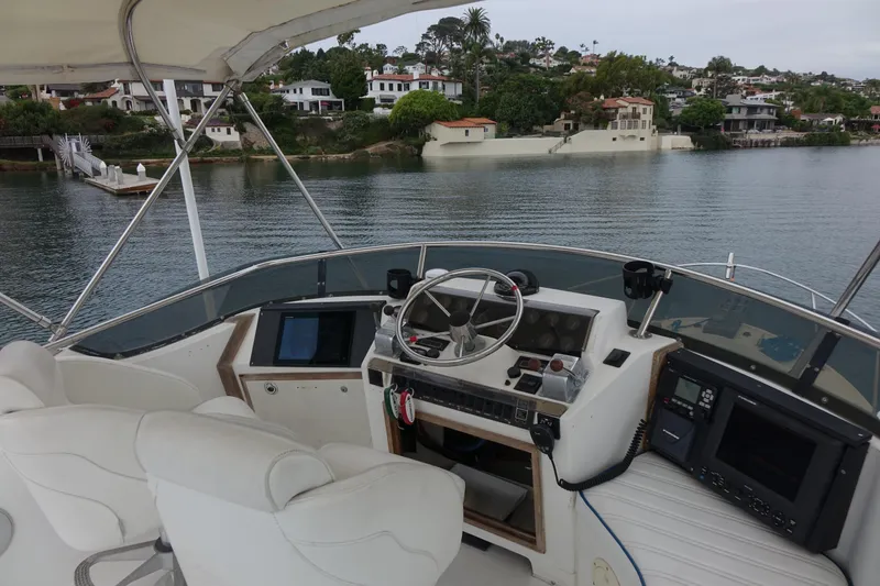 Slide: The Image of 1988 Blackfin 29 Flybridge boat interior with steering wheel and control panel, overlooking waterfront homes. - 17