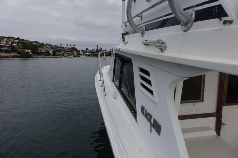 Slide: The Image of 1988 Blackfin 29 Flybridge boat on calm water, showcasing sleek design and coastal scenery. - 21