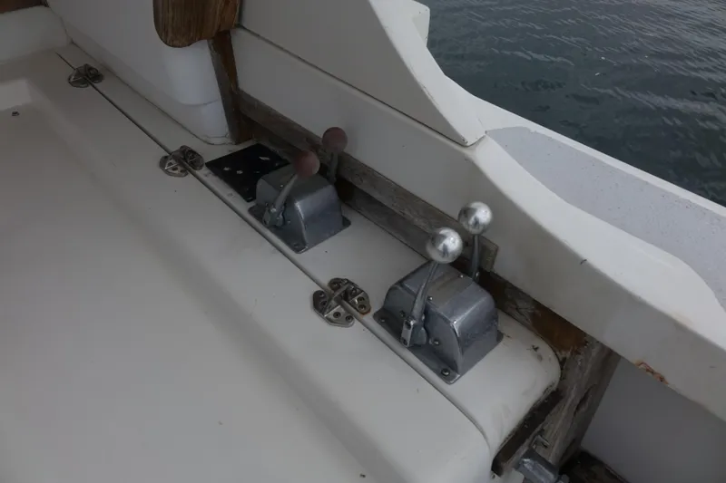 Slide: The Image of 1988 Blackfin 29 Flybridge boat controls, featuring dual levers near water. - 23