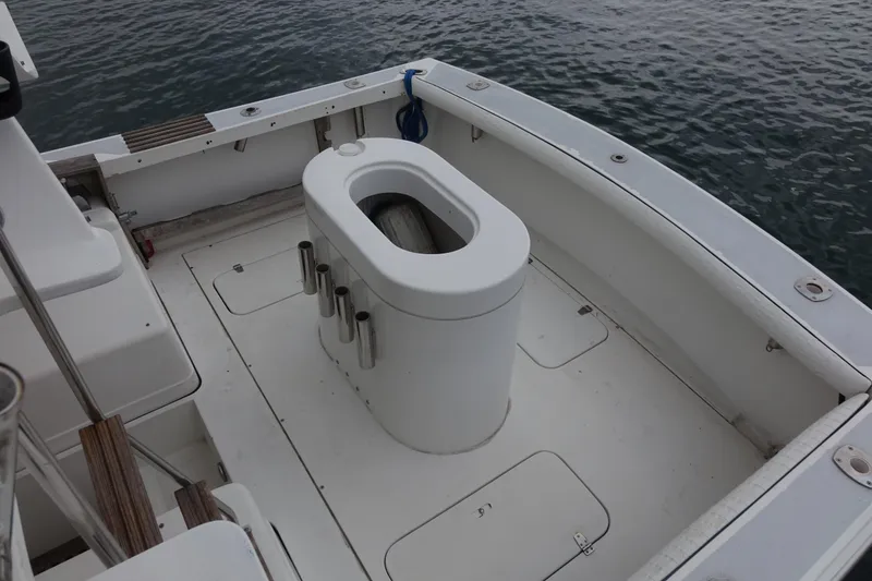 Slide: The Image of 1988 Blackfin 29 Flybridge boat deck with fishing rod holders, docked on calm water. - 26