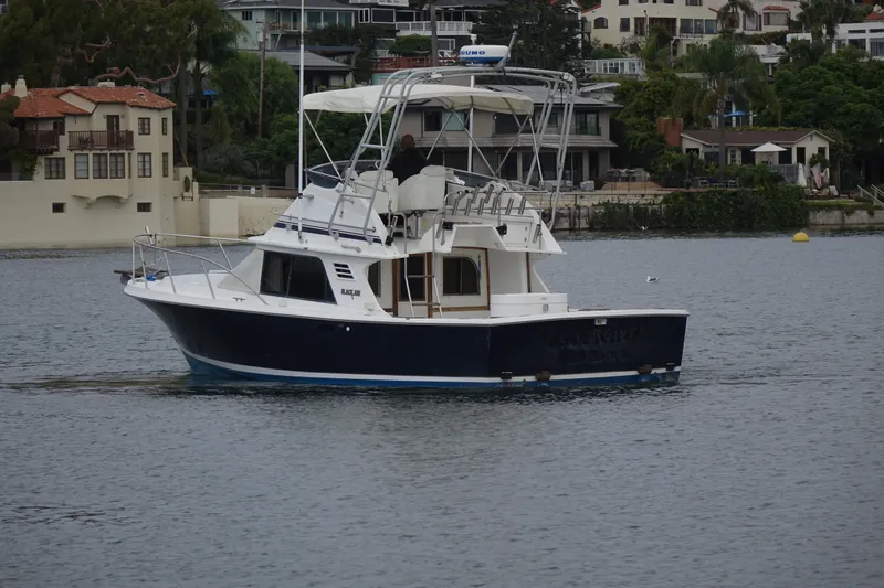 Slide: The Image of 1988 Blackfin 29 Flybridge boat cruising on a calm waterway near residential area. - 3