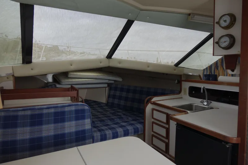 Slide: The Image of 1988 Blackfin 29 Flybridge interior with plaid seating, kitchenette, and large windows. - 31