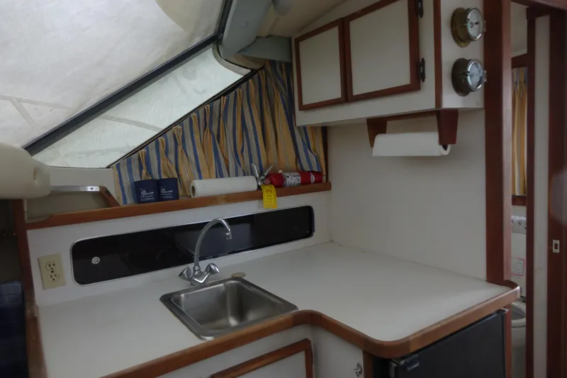 Slide: The Image of 1988 Blackfin 29 Flybridge interior kitchen with sink, cabinets, and striped curtains. - 33