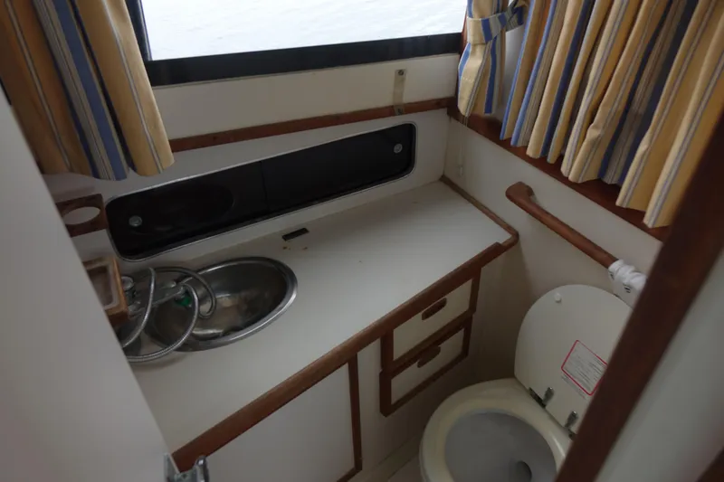 Slide: The Image of 1988 Blackfin 29 Flybridge bathroom with sink, toilet, and striped curtains. - 34